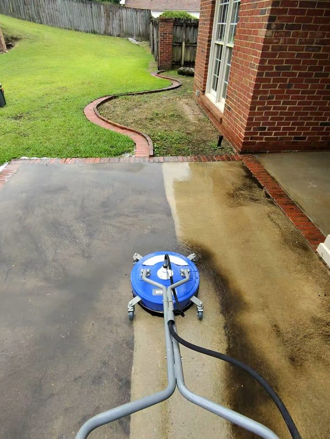 Surface cleaner making a clear clean line on concrete near a brick home