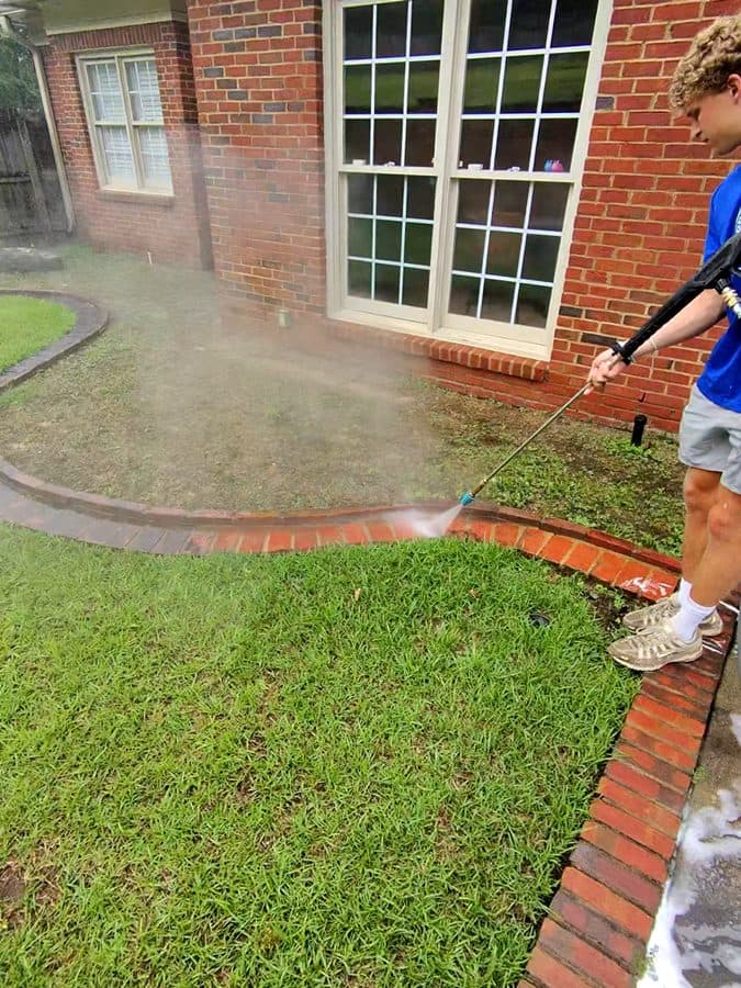 Team Clean cleaning a brick home exterior beside large windows